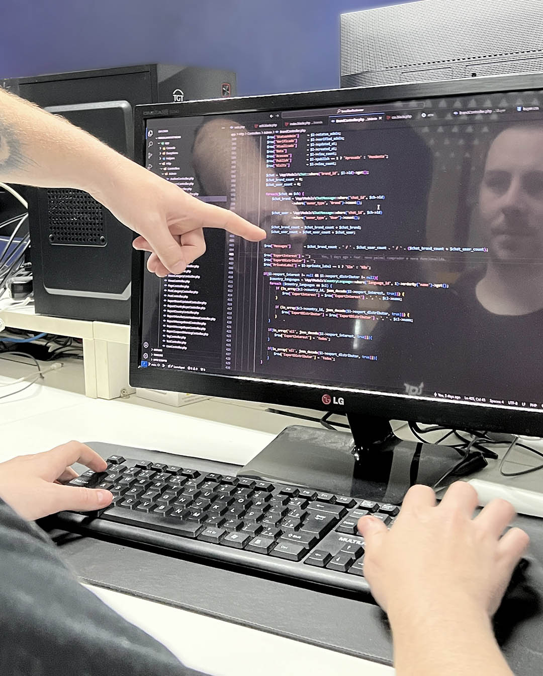 Pessoa digitando em um teclado de notebook com gráficos na tela, um óculos escuro ao seu lado, junto com um celular